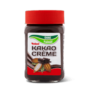 Ein Glas Nudossi®, Kakaocreme ohne Palmöl mit rotem Deckel, mit Kakaobohnen auf dem Etikett und dem Text "OHNE Palmöl", der darauf hinweist, dass dieser Schokoladenaufstrich frei von Palmöl ist.
